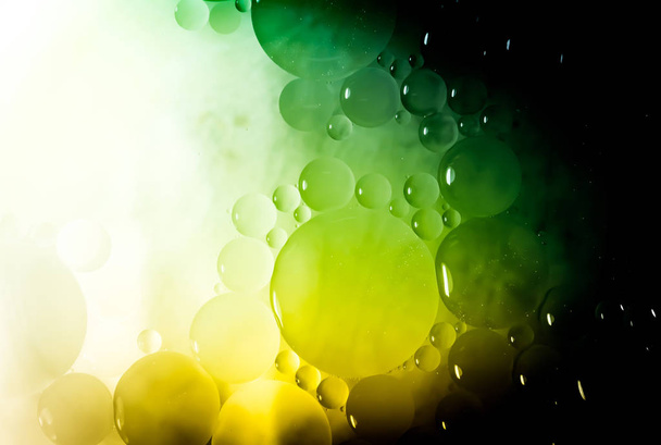 Kreativer Abstraktionshintergrund aus Kreisen unterschiedlicher Größe mit Hintergrundbeleuchtung und Farbverlauf in grüner und gelber Farbe. - Foto, Bild