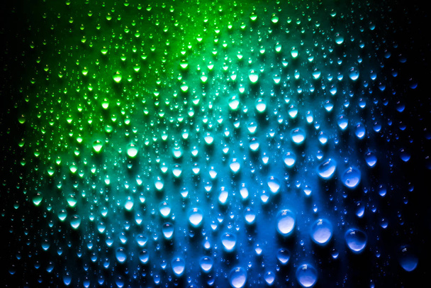 Drops of water with a beautiful bright gradient in green and blue colors closeup macro on the material in the sunlight. - Valokuva, kuva