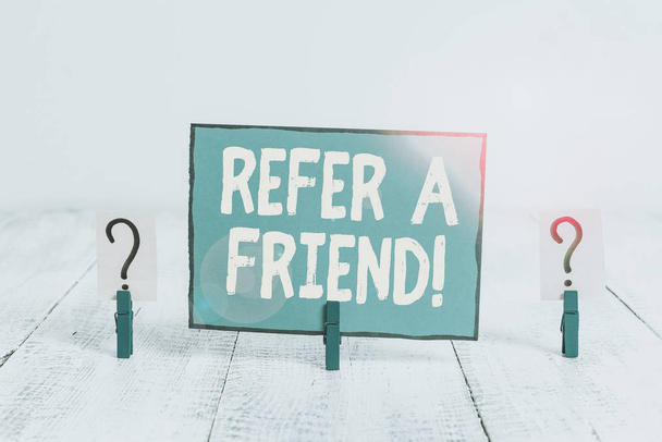 Text sign showing Refer A Friend. Conceptual photo direct someone to another or send him something like gift Scribbled and crumbling sheet with paper clips placed on the wooden table. - Photo, Image