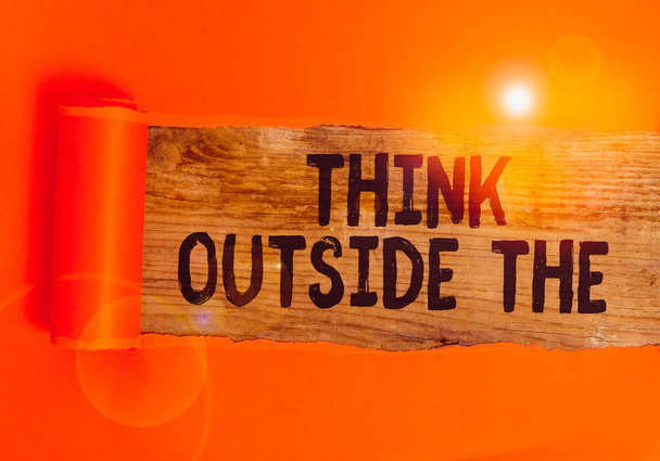 Текст написания слов Think Outside The. Бизнес-концепция для креативного мышления Глядя в другую перспективу Картон, разорванный посередине, помещенный над деревянным классическим столом
. - Фото, изображение