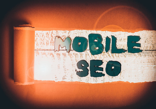 Tekst pisania słów Mobile Seo. Business photo showcasing proces optymalizacji strony internetowej do rangi wyszukiwania mobilnego Tektura, która jest rozdarta w środku umieszczony nad drewnianym klasycznym stole - Zdjęcie, obraz