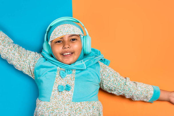 Young muslim Asian girl wearing hijab happily listening to music with headphones - Φωτογραφία, εικόνα