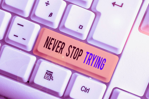 Text sign showing Never Stop Trying. Conceptual photo Do not give up Continue to Try Again Keep on Doing White pc keyboard with empty note paper above white background key copy space. - Photo, Image