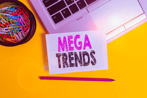 Conceptual hand writing showing Mega Trends. Business photo text powerful phenomena impacting the foundations of our world Trendy laptop pencil squared paper container colored background. - Photo, Image