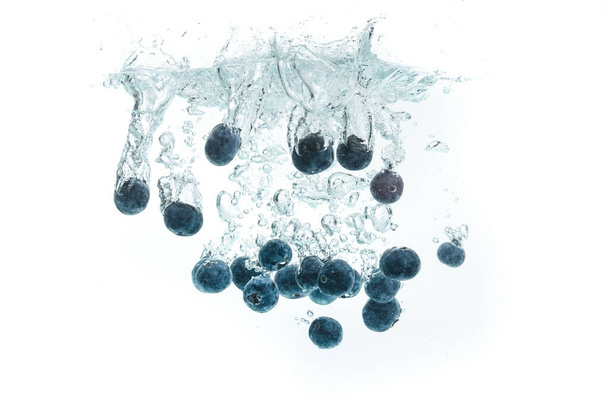 Blueberries falling into water on white background - Фото, зображення