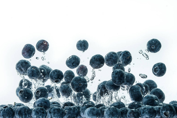 Blueberries falling into water on white background - Fotó, kép