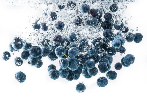 Blueberries falling into water on white background - Valokuva, kuva