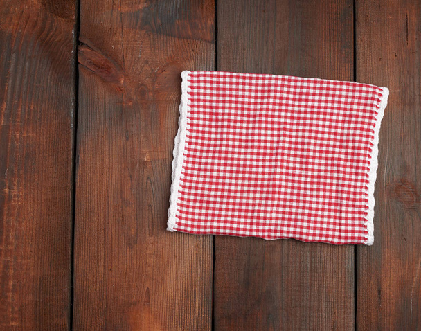 toalla de cocina a cuadros rojo blanco sobre un fondo de madera marrón
 - Foto, Imagen