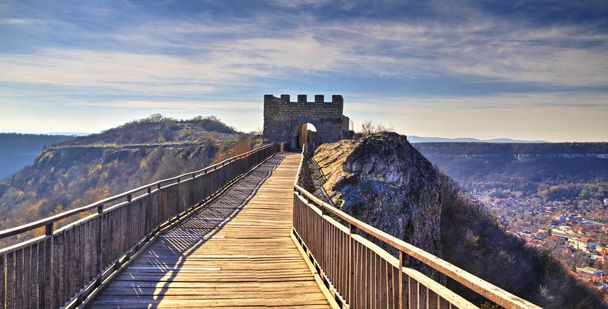 Hermosa vista con puente de madera que conduce a una puerta de piedra de una antigua fortaleza
 - Foto, Imagen