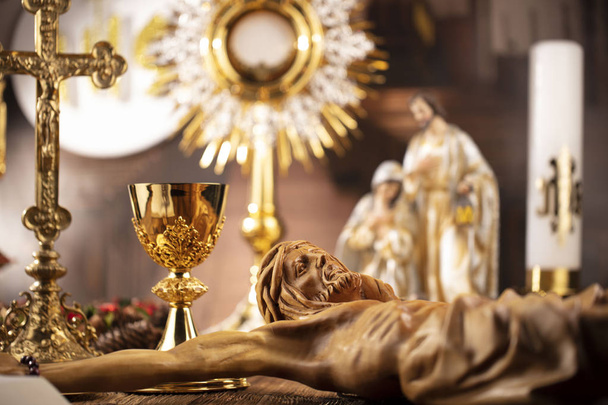 Roman Catholic Church theme. The Cross, Holy Bible, monstrance, rosary and golden chalice on rustic wooden table - Photo, Image