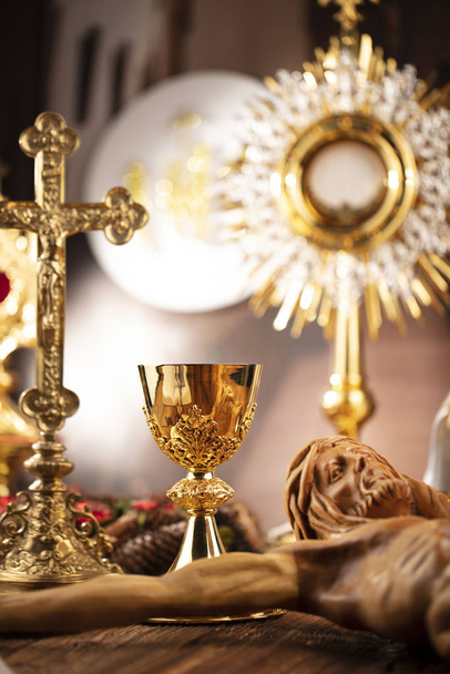 Thema der römisch-katholischen Kirche. Kreuz, Bibel, Monstranz, Rosenkranz und goldener Kelch auf rustikalem Holztisch - Foto, Bild