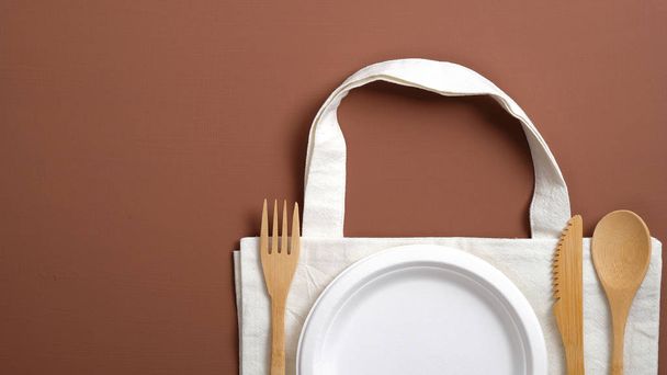 Cotton reusable produce bag with eco-friendly wooden cutlery and carton plate. Zero waste concept. Eco store banner mockup. - Foto, Imagem