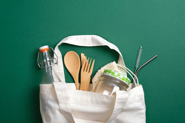 Canvas shopper bag with eco friendly reusable bamboo cutlery, metal drinking straws, glass jar and bottle. Zero waste, plastic free concept. Sustainable lifestyle - Фото, изображение