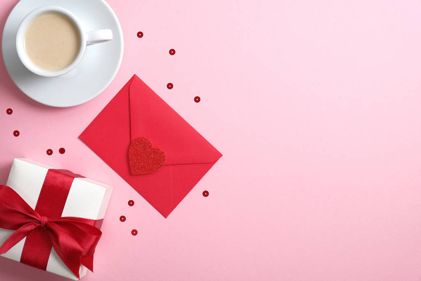 Coffee cup, red paper envelope with love letter and gift box on pink background. Flat lay, top view, copy space. Valentine's day concept. - Fotó, kép
