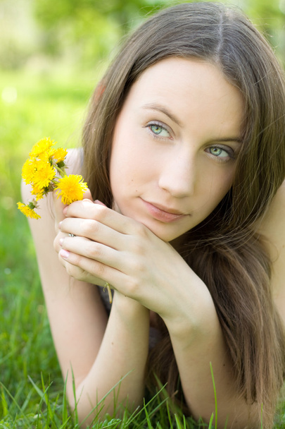 Young beautiful teenager with dandelion on lawn - 写真・画像