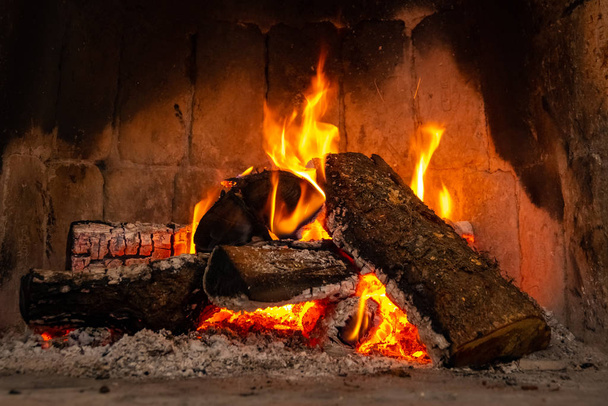 Fire in a fireplace with logs and flames creating a sense of warmth and coziness. - Photo, Image