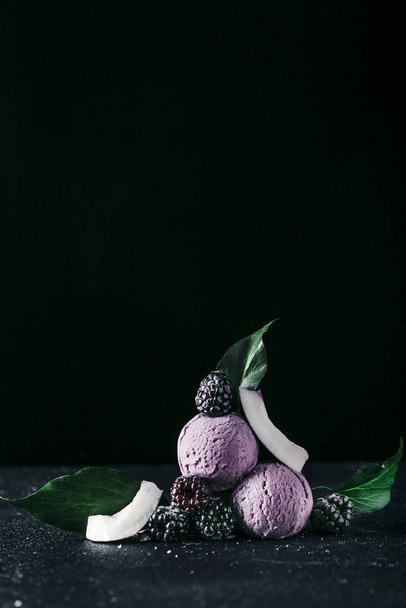 Balls of ice cream with blackberries and slices of coconut on bl - Fotoğraf, Görsel