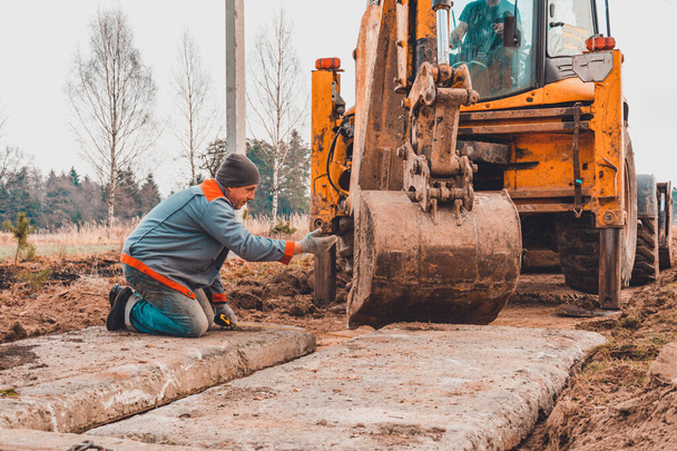A escavadora instala lajes de concreto para a estrada
. - Foto, Imagem
