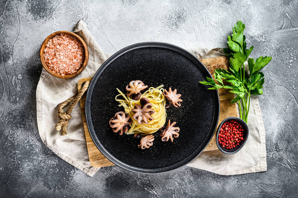 Bavetti pasta with baked octopus. Gray background. Top view - Photo, Image