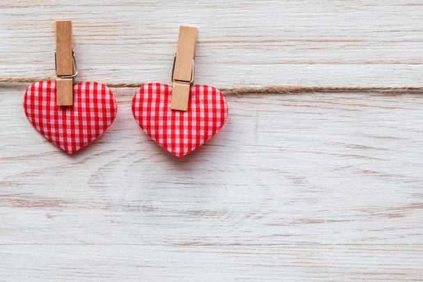 Fondo del día de San Valentín con un par de corazones rojos en pinzas de ropa en el borde de madera. Concepto de San Valentín
 - Foto, Imagen