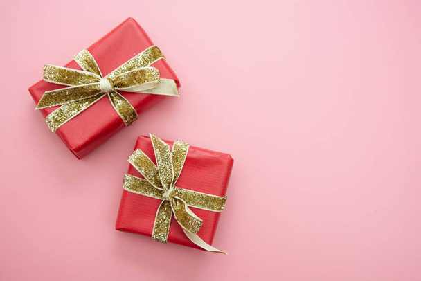 Red gift box and golden bow, on pink background. Valentine's Day, Birthday, Party concept. - Photo, Image