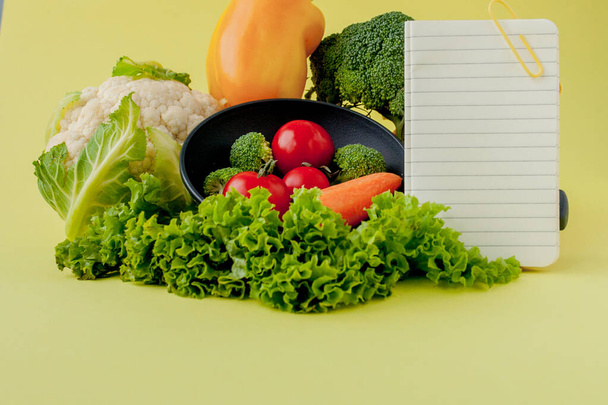 Vegetables and notebook with copy space on yellow background. Bi - Zdjęcie, obraz