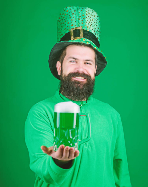 Freshly tapped beer. Hipster in green leprechaun hat holding beer mug. Irish man with beard drinking green beer. Celebrating saint patricks day in bar. Bearded man toasting to saint patricks day - Foto, Imagem