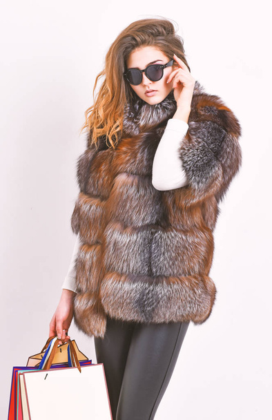 Woman shopping luxury boutique. Lady hold shopping bags. Discount and sale. Buy with discount on black friday. Shopping or birthday gift. Girl wear sunglasses and furry coat shopping white background - Fotoğraf, Görsel