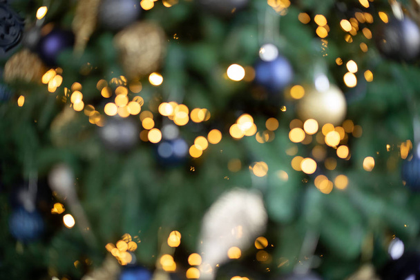 Θολή εικόνα πολύχρωμα μπιχλιμπίδια, λαμπερά χριστουγεννιάτικα φώτα και δώρα κάτω από το χριστουγεννιάτικο δέντρο. Αφηρημένο νέο έτος φόντο - Φωτογραφία, εικόνα