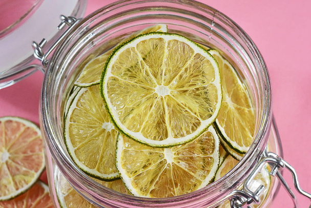Dried lemons and limes in an electric dryer in a glass jar - Photo, Image