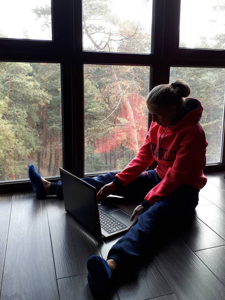 giovane ragazza bionda a casa a lavorare su un computer portatile e parlare al telefono vicino a una grande finestra
 - Foto, immagini