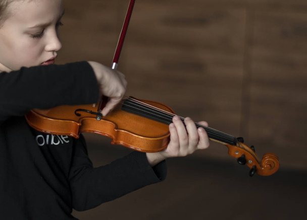 Käsittele viulua. Pieni poika kantaa viulua. Nuori poika soittaa viulua
 - Valokuva, kuva