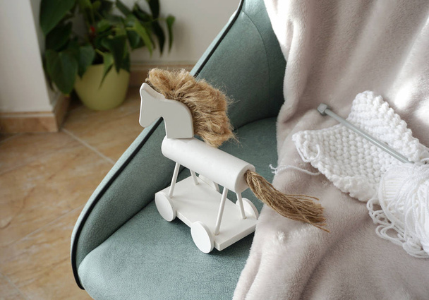 Klasik beyaz tahta at oyuncağı ve rahat koltukta beyaz örgü aksesuarlar. Tatlı ve mutlu ev ayrıntıları - Fotoğraf, Görsel