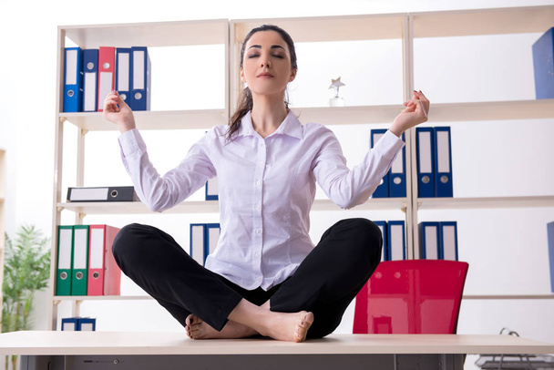 Young female employee doing exercises in the office - Photo, Image