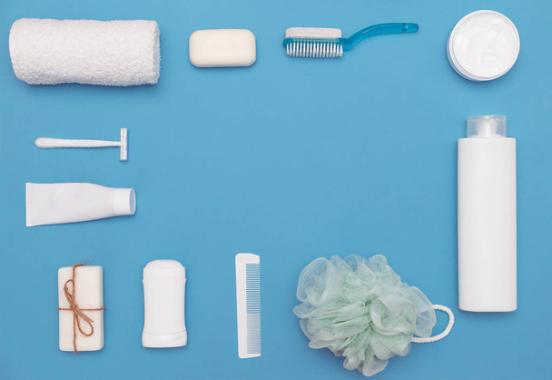 Productos higiénicos para el cuidado del cuerpo y la piel, en envases blancos sobre fondo azul. Acostado. Copiar espacio
 - Foto, Imagen