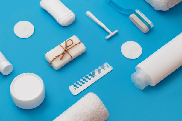 Productos higiénicos para el cuidado del cuerpo y la piel, en envases blancos sobre fondo azul. Acostado. Copiar espacio
 - Foto, Imagen