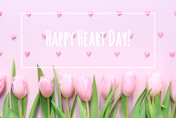 Happy Heart Day z różowymi tulipanami i posypką różowe serce na różowym tle. Płaskie łóżko, widok z góry. Walentynki - Zdjęcie, obraz