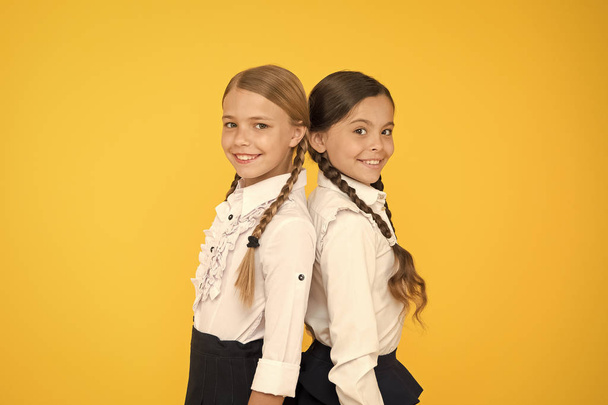 Making everything right. According to school rules. Classmates tidy pupils. Educational program for gifted kids. Best pupils award. Excellent pupils. Girls perfect uniform outfit on yellow background - Foto, afbeelding