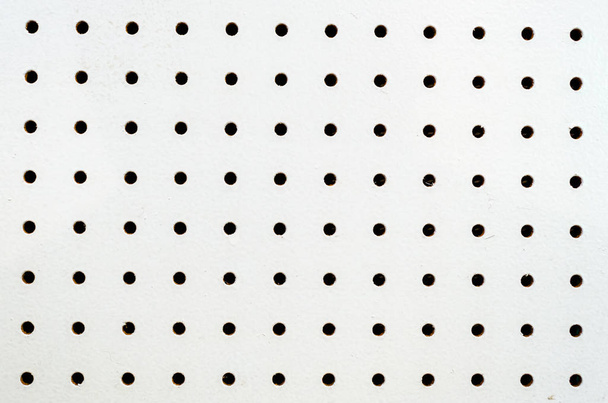 Symetryczne otwory na białej tablicy - Zdjęcie, obraz