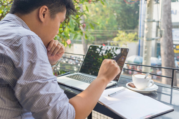 Inversor asiático viendo el cambio de la bolsa en el ordenador portátil
 - Foto, imagen