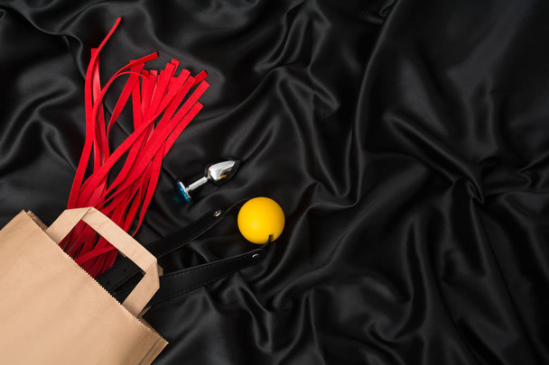 Červený bič, roubík, anální kolík na černém hedvábí. Příslušenství pro dospělé sexuální hry. Hračky pro pásmo - Fotografie, Obrázek