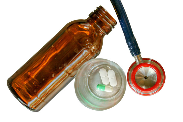 Vista superior del médico pequeño estetoscopio, vidrio de la medicina y frasco de medicina marrón sobre fondo blanco aislado
. - Foto, Imagen