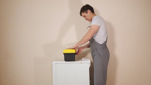 επισκευαστής ανατροπές βίδες σε σπασμένο πλυντήριο κοντά στον τοίχο - Πλάνα, βίντεο