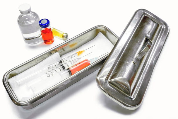 Vaccin en flacons et seringues en plastique avec aiguilles médicales dans un récipient médical en acier inoxydable pour injection immédiate au patient sur fond blanc
. - Photo, image
