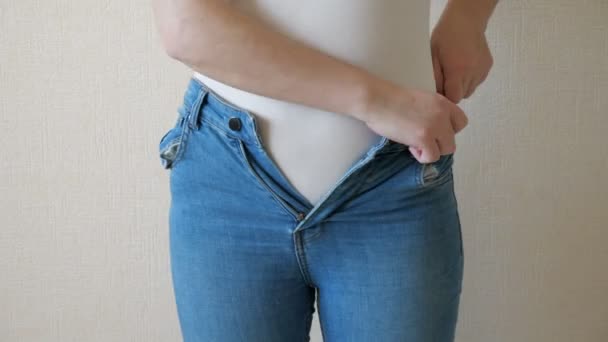 Молодая женщина изо всех сил старается застегнуть джинсы
 - Кадры, видео