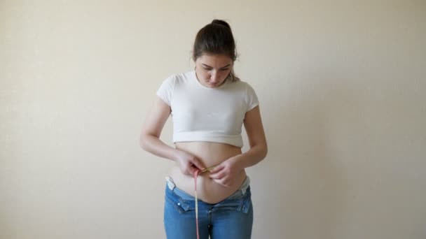 Egy kövér nő egy centiméteres szalaggal méri a derekát. - Felvétel, videó