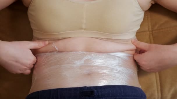 Close-up de uma barriga de mulher, que é enrolado em plástico
 - Filmagem, Vídeo