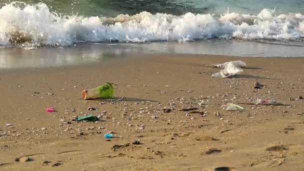 plastic beker en afval op het strand en de golven bliezen ze in de zee - Video