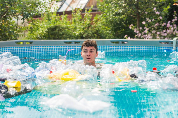 Ökologie, Plastikmüll, Umweltnotstand und Wasserverschmutzung - geschockter Mann schwimmt in schmutzigem Schwimmbad - Foto, Bild