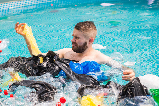 Ökologie, Plastikmüll, Umweltnotstand und Wasserverschmutzung - geschockter Mann schwimmt in schmutzigem Schwimmbad - Foto, Bild